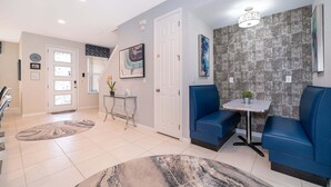 A modern interior with a seating area, a small table, and a door leading to another room. - 3BR Solara Resort Home with Private Pool, BBQ & Resort Amenities Near Disney (Kissimmee)