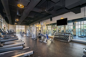 Une salle de sport équipée de tapis de course, d’appareils de musculation et d’haltères.