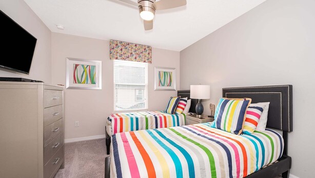 A bedroom with two beds, a ceiling fan, a dresser, and artwork on the walls. - 3BR Solara Resort Home with Private Pool, BBQ & Resort Amenities Near Disney (Kissimmee)