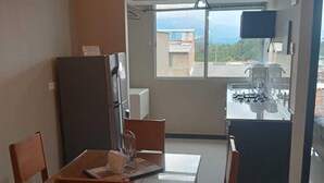 Eine kompakte Küche mit Gasherd, Kühlschrank und einer kleinen Essecke mit Tisch und Stühlen.