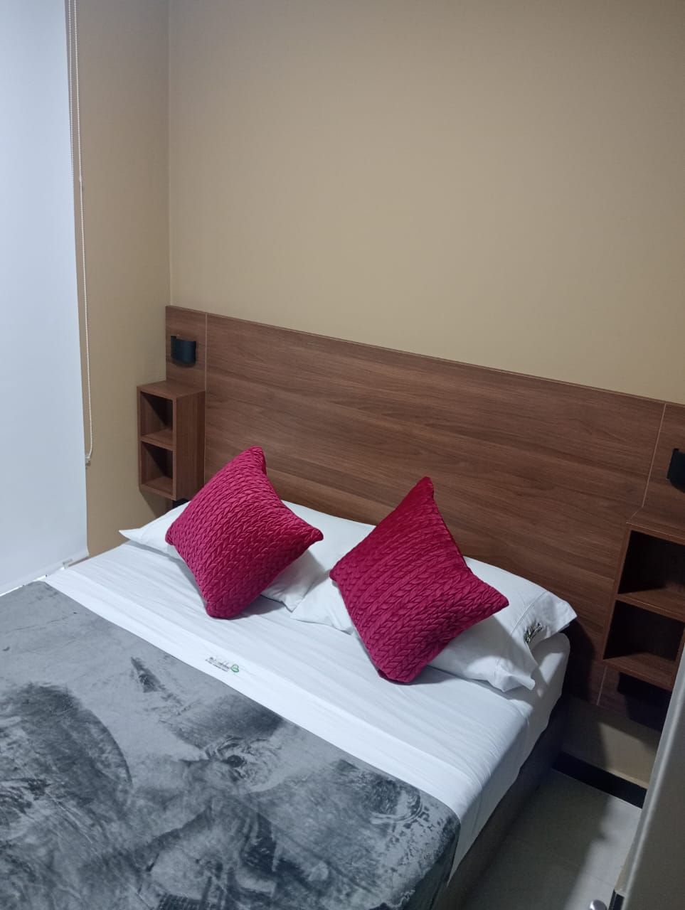 A bed with a wooden headboard, two pillows, and a marble-patterned bedspread.