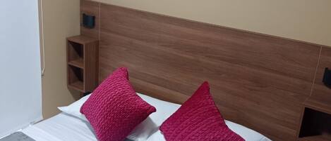 A bed with a wooden headboard, two pillows, and a marble-patterned bedspread.