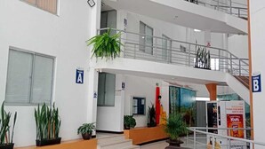 Eine mehrstöckige Hotelhalle mit einer zentralen Treppe, Blumentöpfen, einer Sitzecke mit Sofas und einem Couchtisch.
