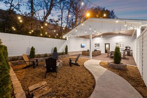 An outdoor patio area with seating, a fire pit, and string lights. - North Nashville 15mins to Broadway Luxury Listing (Goodlettsville)