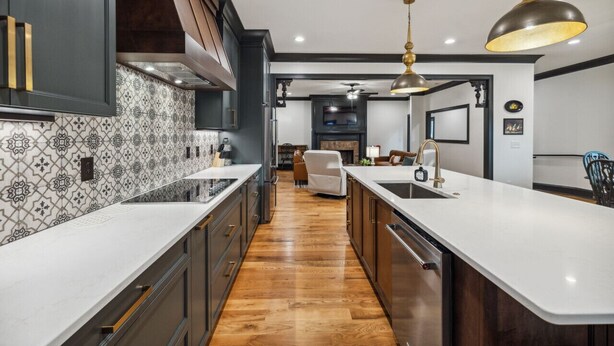 A modern kitchen with a central island, dark cabinetry, and patterned backsplash. - North Nashville 15mins to Broadway Luxury Listing (Goodlettsville)