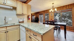Eine Küche mit Holzschränken, Granit Arbeitsplatten, einem integrierten Geschirrspüler und einem Essbereich mit Tisch und Stühlen.