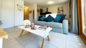 A modern living room with a sofa, a coffee table, and a kitchen area in the background.