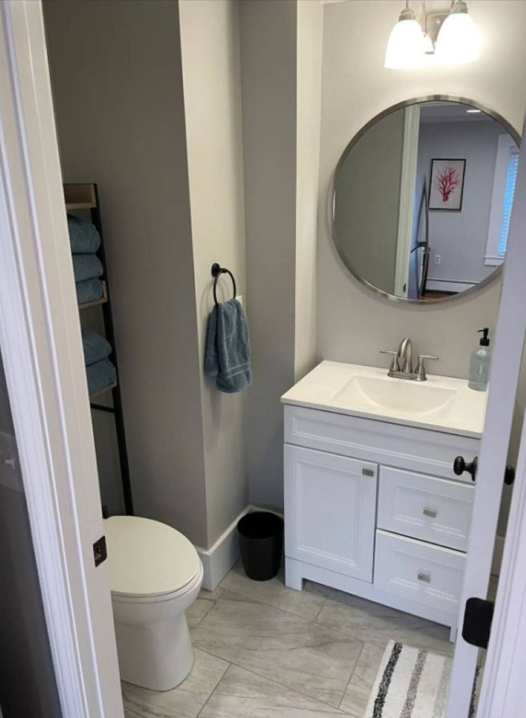 A bathroom with a toilet, a sink, a mirror, and a towel rack.