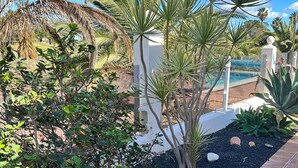 A landscaped area with palm trees, a small pool, and a tiled walkway. - Luxury 3 bedroom villa overlooking golf course with private pool and Wi-fi (Caleta De Fuste)