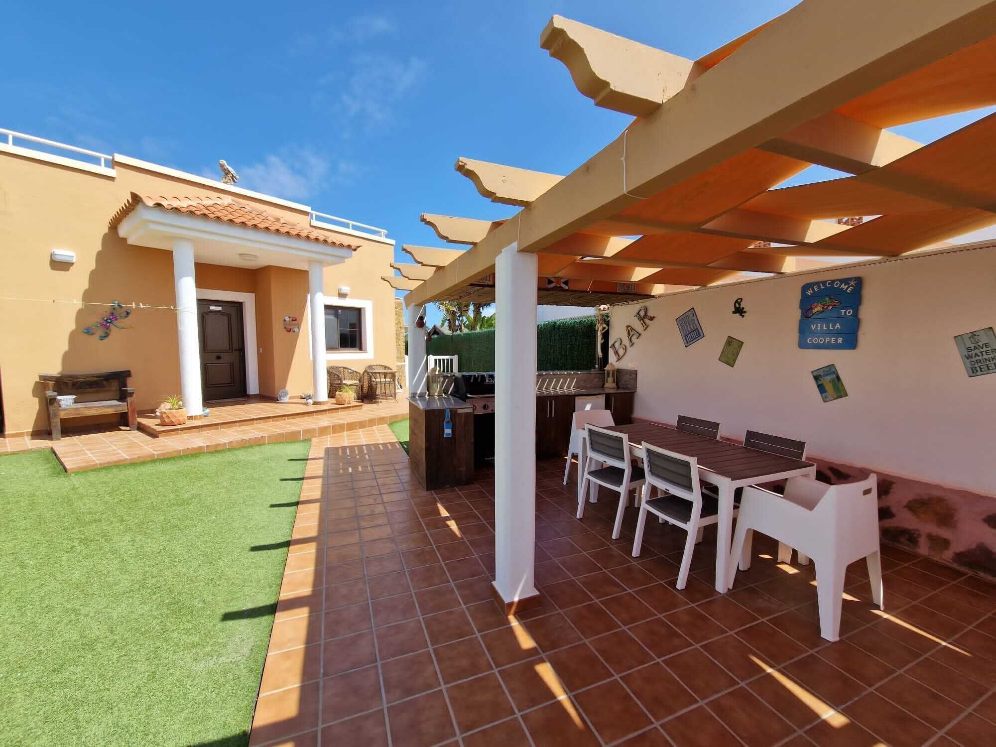 A patio area with a barbecue setup, outdoor seating, and a welcome sign.