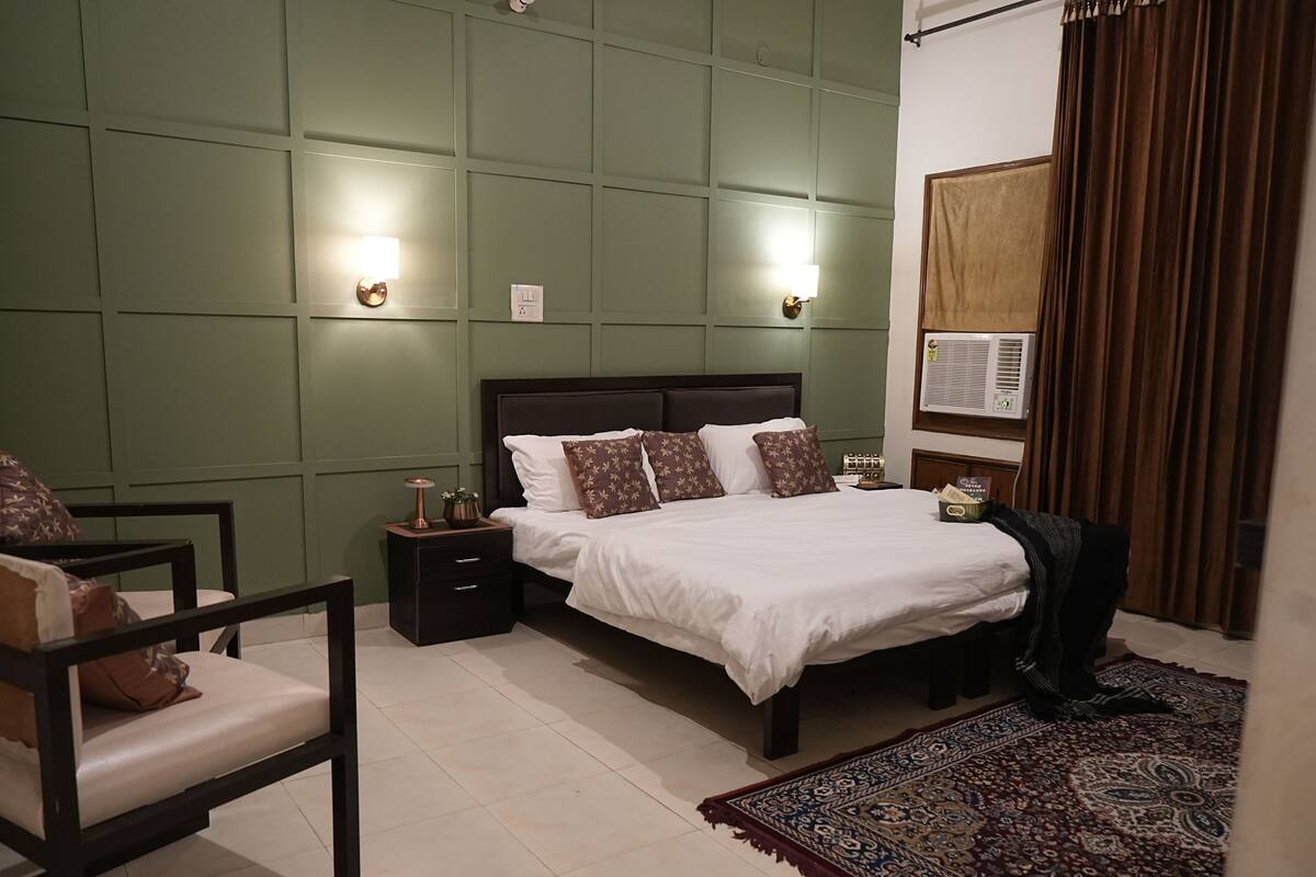 A neatly arranged bedroom with a bed, bedside tables, a chair, and a patterned rug.