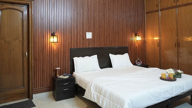 Ein Schlafzimmer mit einer holzverkleideten Wand, einem Bett mit weißer Bettwäsche, zwei Nachttischen und Wandleuchten.