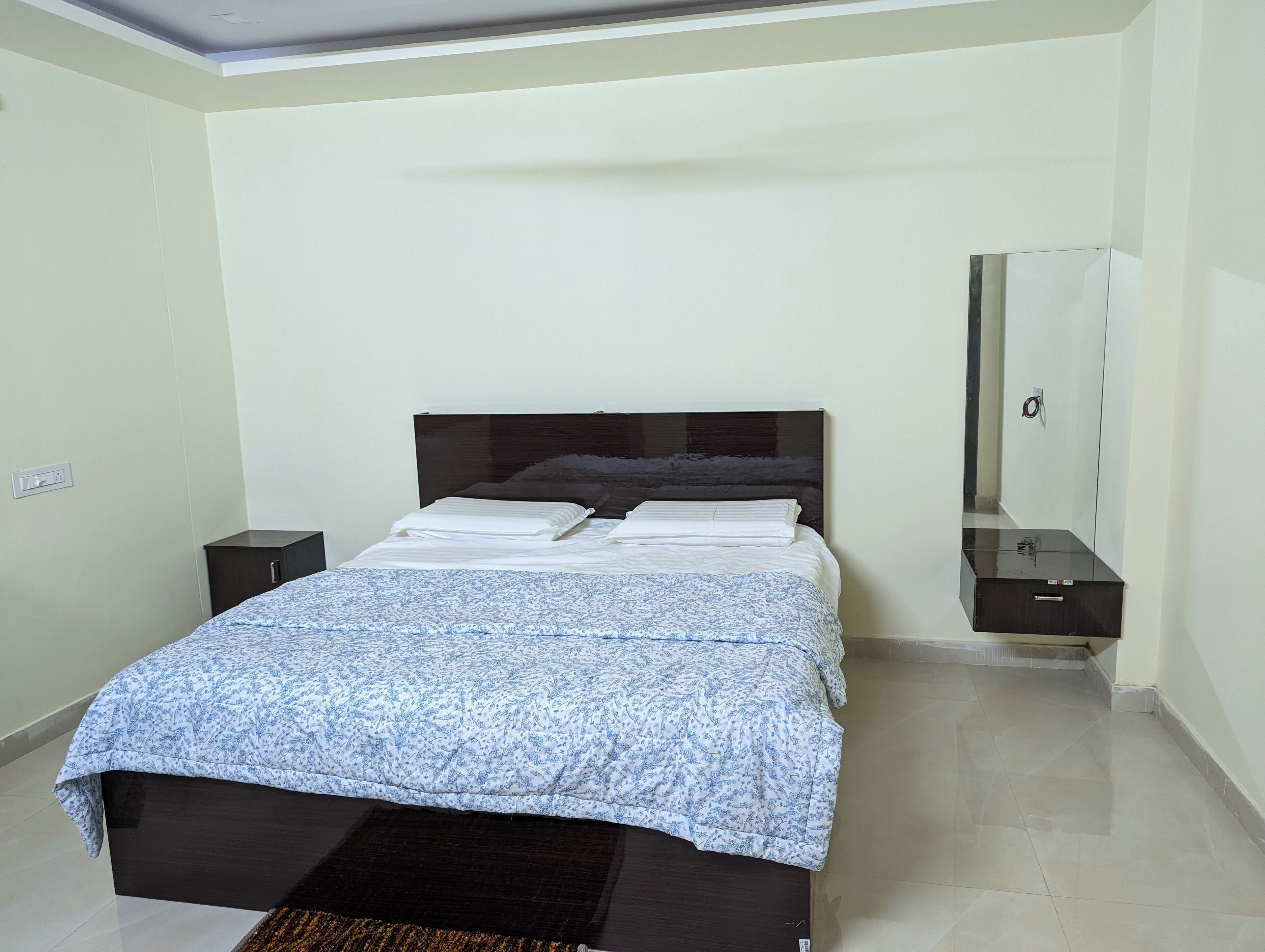 A bedroom with a bed, a nightstand, a dresser, and a mirror.