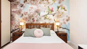 Ein Schlafzimmer mit einem großen Bett, zwei Nachttischen und einer Wandmalerei von Kirschblüten.