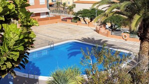Ein Swimmingpool mit klarem, blauem Wasser, umgeben von einer gefliesten Terrasse und Palmen.