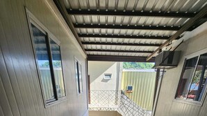 A staircase leading to a covered outdoor area with a view of a building. - Eyy Hostel (El Nido)