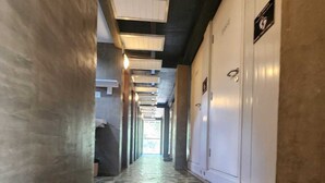 A hallway with patterned flooring, white walls, and a ceiling with exposed beams. - Eyy Hostel (El Nido)