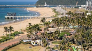 Un resort frente a la playa con un muelle, palmeras y vistas al mar.