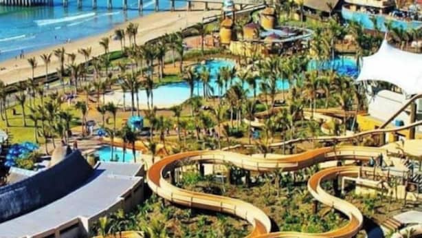 Parque acuático con toboganes serpenteantes y piscinas rodeadas de palmeras.