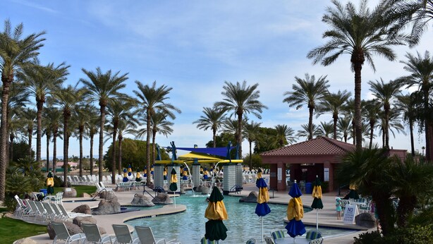 A pool area with lounge chairs, umbrellas, and palm trees. - Entertainment Friendly Home in “The Grand” - Surprise, AZ! (Surprise)