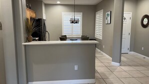 A kitchen with a central island, recessed lighting, and a window with blinds. - Entertainment Friendly Home in “The Grand” - Surprise, AZ! (Surprise)