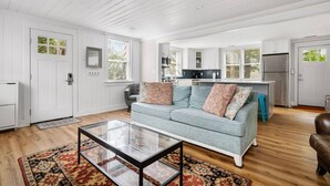 A spacious living room with a light blue sofa, a glass coffee table, and a patterned rug. - Folly Beach Compound - Near the Beach & Center St! (Folly Beach)
