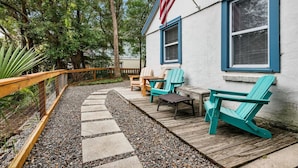 A wooden deck with Adirondack chairs, a small table, and a flag.
