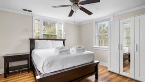 A bedroom with a bed, a ceiling fan, and a wardrobe.
