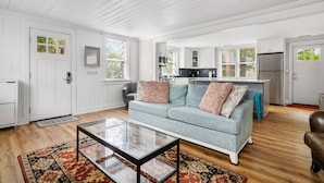A spacious living room with a light blue sofa, a glass coffee table, and a patterned rug.