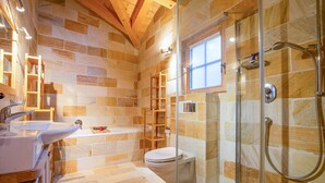 A bathroom with stone walls, a glass shower enclosure, a white toilet, and a sink with a mirror. - Nicande - EXCEPTIONAL & LUXE chalet 8 pers (Haute-Nendaz)