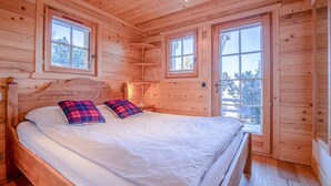 A wooden cabin bedroom with a bed, two windows, and a door leading outside. - Nicande - EXCEPTIONAL & LUXE chalet 8 pers (Haute-Nendaz)