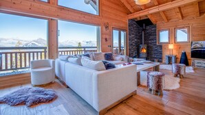A spacious living room with a large sofa, a fireplace, and a view of mountains. - Nicande - EXCEPTIONAL & LUXE chalet 8 pers (Haute-Nendaz)