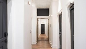 A narrow hallway with white walls and dark wooden flooring. - The Harriss (Wilson)