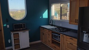 Une cuisine compacte équipée d’un four à micro-ondes, d’une cuisinière, d’un évier et d’un réfrigérateur.