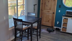 Un coin repas avec une table et des chaises en bois, une vue par la fenêtre et une porte avec un panneau en bois.