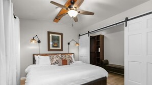 Ein Schlafzimmer mit einem Bett, einem Deckenventilator, einem Bücherregal und einer Schiebetür.