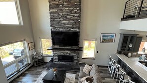 Ein großzügiges Wohnzimmer mit Kamin aus Stein, bequemen Sitzgelegenheiten und einer Bar.