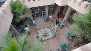 A courtyard with outdoor seating, a fountain, and palm trees.