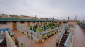 A rooftop terrace with potted plants, outdoor seating, and a view of the cityscape. - Riad Golden Mansour  (Meknes)