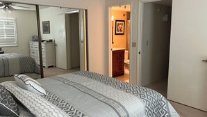Un dormitorio con cama, cómoda, espejo y puerta que da a otra habitación.