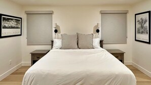 Une chambre à coucher avec un grand lit, deux tables de chevet et deux lampes fixées au mur.