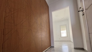 A hallway with a wooden wall featuring geometric patterns, a marble floor, and a door with a handle. - Villa The Crown  (Ariana)