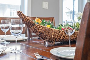 Una mesa de comedor con un centro de mesa de mimbre, copas de vino, platos y cubiertos.
