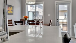 A modern dining area with a white table, two wine glasses, and a vase with flowers. - Luxury in Laurel-8 guests+1 Baby,4 beds,2.5 bath,Dbl Grg,discount w direct book. (Edmonton)