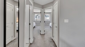 A hallway with white doors leading to bedrooms, carpeted floors, and a ceiling light. - Luxury in Laurel-8 guests+1 Baby,4 beds,2.5 bath,Dbl Grg,discount w direct book. (Edmonton)