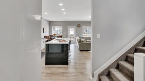 A modern kitchen with a central island, a dining area with chairs, and a staircase leading to another level. - Luxury in Laurel-8 guests+1 Baby,4 beds,2.5 bath,Dbl Grg,discount w direct book. (Edmonton)