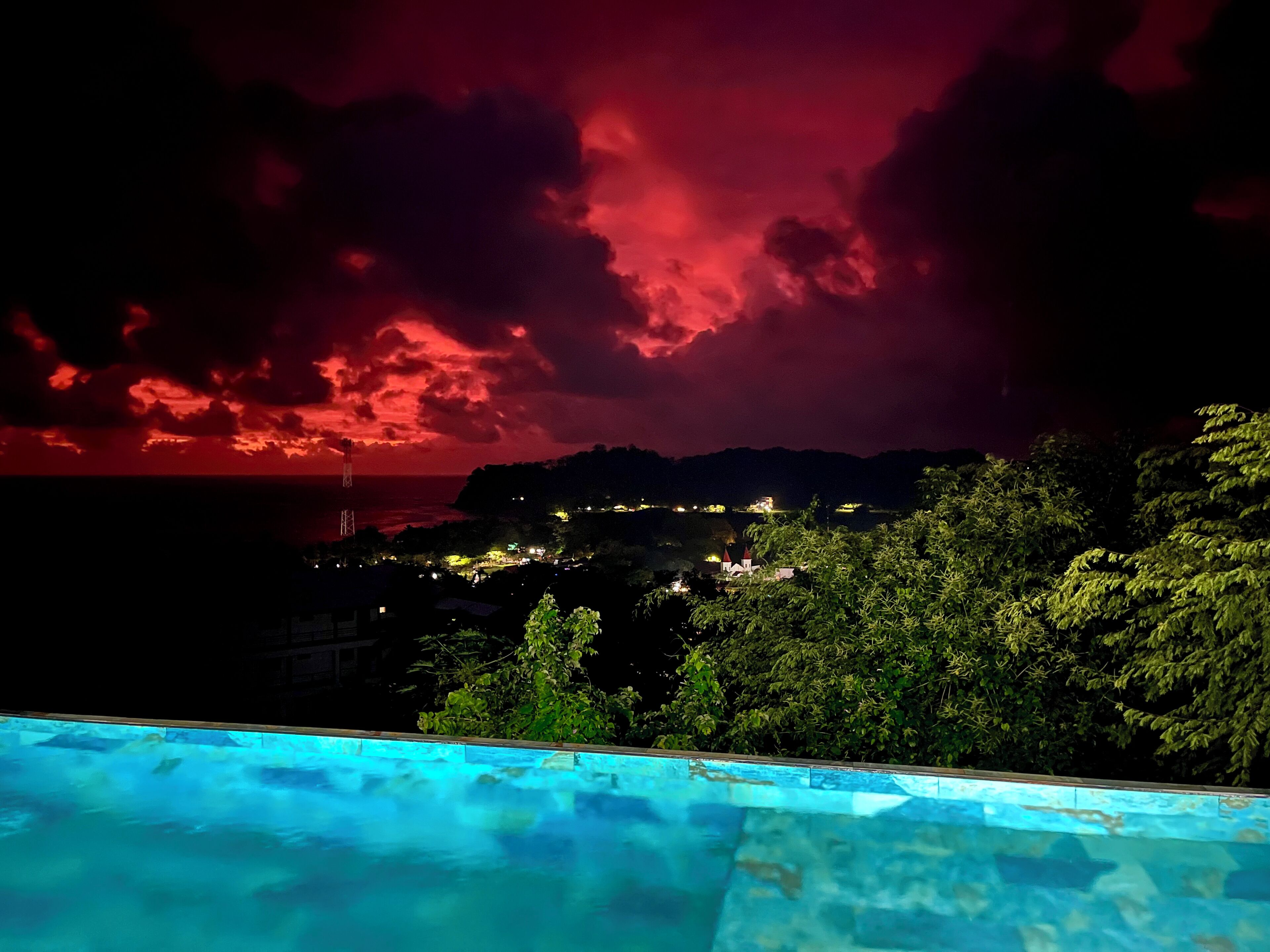 A nighttime view of a pool with a red sky in the background.