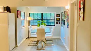 A modern kitchen with white appliances and a dining area with a glass table and chairs.