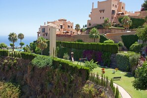 A coastal hotel with terraced gardens, palm trees, and a clear view of the sea. - Great Apartment With View (Mijas)