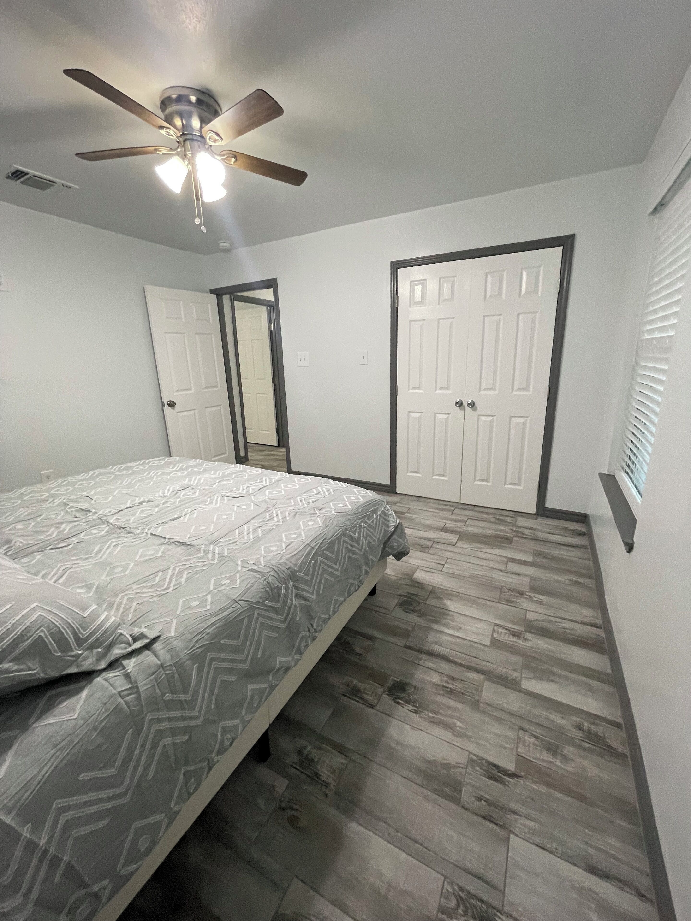 Un dormitorio con cama, ventilador de techo y dos puertas.